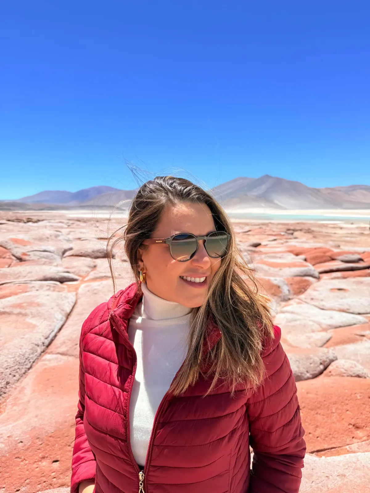 Paisagem do Atacama, com lagoa e cordilheira; no celular, viajante diante do deserto